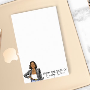 May include: A white notepad with a black and white illustration of a woman wearing a leopard print jacket. The notepad has the text "From the desk of Emily Renee" at the bottom.