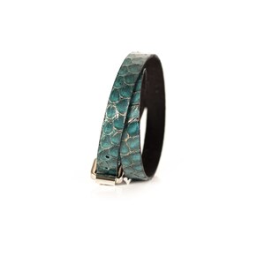 May include: A teal leather bracelet with a silver buckle. The bracelet is made of two strands of leather that are woven together.