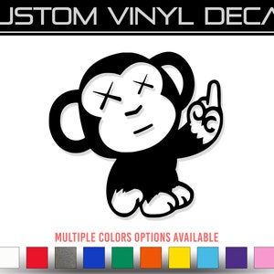 May include: Black and white vinyl decal of a monkey with an X for eyes and a middle finger raised. The monkey is wearing a simple, cartoonish expression.