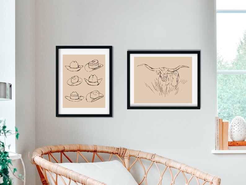 May include: Two black framed prints on a white wall. The print on the left features a line drawing of six cowboy hats. The print on the right features a line drawing of a longhorn steer.