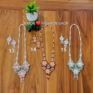 May include: Three sets of beaded jewelry labeled 13, 14, and 15, each featuring a long necklace and matching earrings. The necklaces have intricate geometric and floral patterns in red, yellow, blue, and white beads with dangling fringe elements.