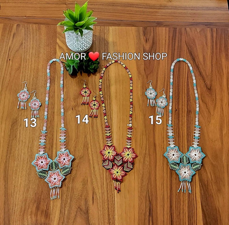 May include: Three sets of beaded jewelry labeled 13, 14, and 15, each featuring a long necklace and matching earrings. The necklaces have intricate geometric and floral patterns in red, yellow, blue, and white beads with dangling fringe elements.