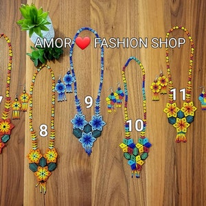 May include: Six sets of beaded necklaces and matching earrings labeled AMOR FASHION SHOP with numbers 7 through 12. Each set features intricate floral patterns made from small colorful beads in various combinations of red, yellow, blue, and green.