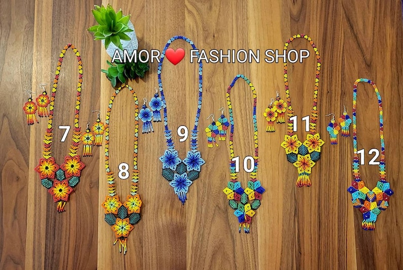 May include: Six sets of beaded necklaces and matching earrings labeled AMOR FASHION SHOP with numbers 7 through 12. Each set features intricate floral patterns made from small colorful beads in various combinations of red, yellow, blue, and green.