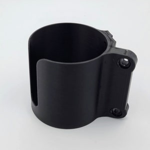 May include: A black plastic cup holder with two screws on the side. The holder is designed to attach to a surface.