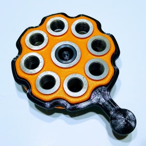 May include: A black and orange tool with a handle and eight circular holes. The tool is designed for crafting and has a textured surface.