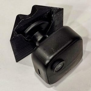 Peut inclure: Un support d'appareil photo de sécurité noir imprimé en 3D. Le support est conçu pour maintenir la caméra en place de manière sécurisée et permet un réglage facile de l'angle de la caméra.
