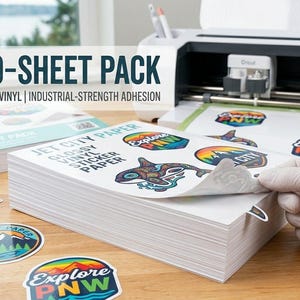 May include: A stack of white vinyl sticker paper sheets with the text "BULK 50-SHEET PACK" and "WATERPROOF GLOSSY VINYL | INDUSTRIAL-STRENGTH ADHESION". The image shows a person peeling a sticker from the stack. Colorful stickers with nature-themed designs are scattered around.