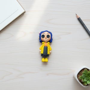 Coraline figurine displayed on office desk with spooky cute aesthetic
