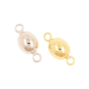 May include: Two oval-shaped jewelry connectors, one in a silver tone and one in a gold tone. Each connector features a smooth, polished surface with a small circular loop attached to both the top and bottom ends for linking components.