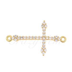 May include: Gold-toned cross charm with clear cubic zirconia stones. The cross has a loop on each side for attaching to a chain or bracelet.