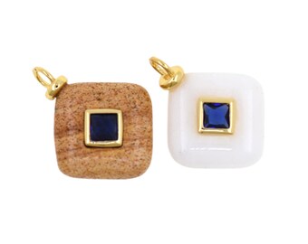 May include: Two square pendants. One is a light brown, textured stone with a dark blue square in the centre, framed in gold. The other is white with a dark blue square and gold frame. Both have gold loops.