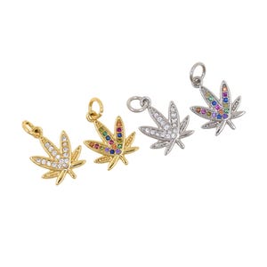 May include: Four cannabis leaf charms in gold and silver. Two gold charms feature clear and multi-coloured gemstones. The silver charms have clear and multi-coloured gemstones. Each charm has a small loop for attaching to a necklace or bracelet.