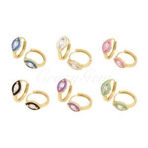 Op de afbeelding: Goudkleurige oorringen met een marquise-vormige bedel. Elke bedel heeft een centrale heldere steen en een gekleurde emaille rand in blauw, wit, roze, zwart, paars en groen. De oorbellen worden gepresenteerd tegen een witte achtergrond.