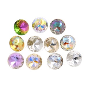 Puede incluir: Una colección de cuentas de cristal facetadas e iridiscentes en varios colores. Las cuentas son redondas y reflejan la luz, mostrando un espectro de tonos que incluyen verde, morado y transparente. Estos cristales decorativos son ideales para la fabricación de joyas y proyectos de artesanía.