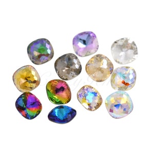 Op de afbeelding: Een verzameling iriserende, vierkant geslepen strass-steentjes in verschillende kleuren, waaronder goud, paars en helder. Deze decoratieve edelstenen hebben een facetontwerp dat licht reflecteert. Ideaal voor knutselen en versieringen.