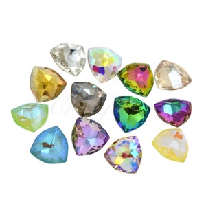 Op de afbeelding: Een verzameling iriserende, driehoekige strass-steentjes in verschillende kleuren, waaronder helder, goud, groen en paars. Deze facetgeslepen edelstenen zijn verspreid tegen een witte achtergrond, reflecteren licht en creëren een sprankelend effect. Ideaal voor knutselen en versieren.