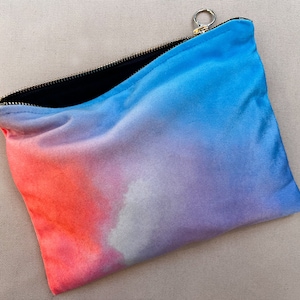 Peut inclure: Une pochette zippée en velours bleu, rose et blanc avec un tirette de fermeture éclair dorée.