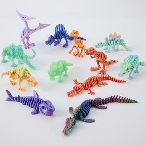 May include: A collection of twelve articulated plastic animal and dinosaur skeleton figures in various colors, including a purple shark, orange crocodile, green triceratops, blue spinosaurus, pink pterodactyl, and other multi-colored prehistoric creatures.