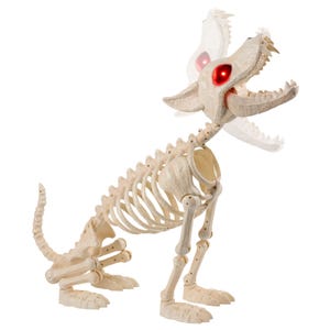 May include: A beige plastic dog skeleton figure in a seated position with a rib cage, articulated limbs, and a tail. The skull features an open jaw with visible teeth and glowing red LED eyes, with a motion blur effect on the head.