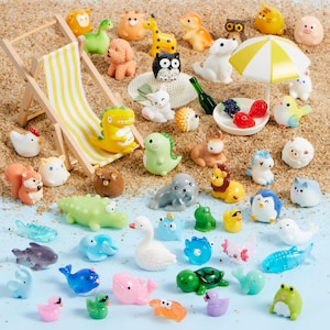 May include: A collection of miniature animal figurines including a yellow dinosaur, a white swan, a green turtle, and various sea creatures, arranged around a small wooden beach chair with yellow stripes and a matching yellow and white beach umbrella.
