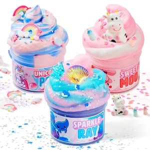 May include: Three clear plastic jars filled with colorful textured slime. One jar labeled Unicorn Pop features blue and pink swirls with rainbow charms. Another labeled Sweet Moo has pink and white swirls with a cow figure. The third labeled Sparkle Ray has blue and purple swirls with a seashell charm.