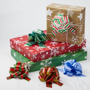 May include: Three rectangular gift boxes stacked together, wrapped in red, green, and gold paper with snowflake and star patterns. The boxes are topped with decorative, multi-colored ribbon bows in red, green, blue, and white striped designs.