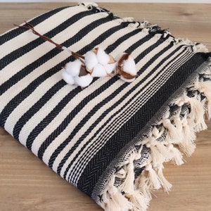 May include: Black and white striped throw blanket with fringe. The blanket is made of cotton and has a soft, textured feel.
