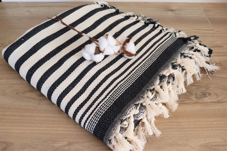 May include: Black and white striped throw blanket with fringe. The blanket is made of cotton and has a soft, textured feel.