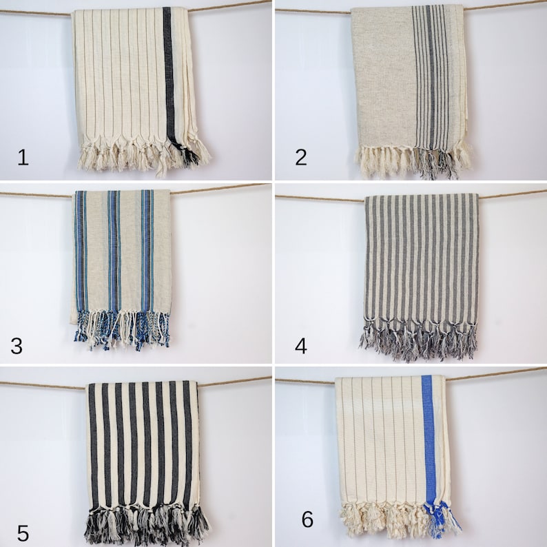 May include: Six different striped towels hanging on a clothesline. The towels are all white with different colored stripes. The towels are all fringed on the bottom.