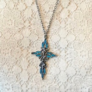 This vintage ZUNI styLe Petit PoiNT CroSS NECKLACE is a great pretender!  Turquoise plastic cabochons mimic the petit point jewelry the Zuni Indians are famous for.  They're set in a silver tone metal.  It's a pretty little western cross that comes on a really nice silver rolo chain.  The links have a  nice stamped line pattern.  You'll receive the pendant and 24" chain.
