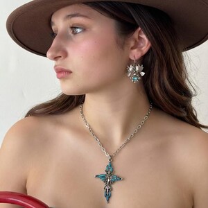 This vintage ZUNI styLe Petit PoiNT CroSS NECKLACE is a great pretender!  Turquoise plastic cabochons mimic the petit point jewelry the Zuni Indians are famous for.  They're set in a silver tone metal.  It's a pretty little western cross that comes on a really nice silver rolo chain.  The links have a  nice stamped line pattern.  You'll receive the pendant and 24" chain.