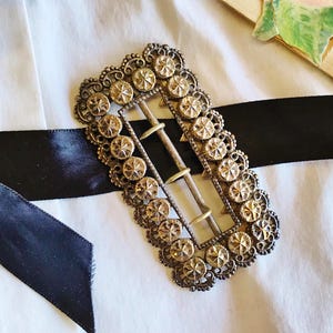 This vintage ViCTORIAN StERLiNG SASH BUCKLE is an amazing!  It's a whopping 3-1/4" long and has Delicate lacy filigree edges and faceted circles of silver that twinkle and shine.  There are 3 sharp prongs that swivel back and forth on a hinge.  There is also a second piece of metal on the back with 4 prongs that also swivels...perhaps to hold the material secure.  It's in great condition and would look glorious on a wedding belt.  Original Patina or very tarnished.