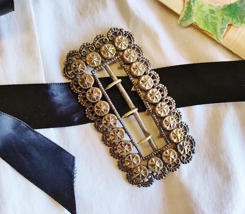 This vintage ViCTORIAN StERLiNG SASH BUCKLE is an amazing!  It's a whopping 3-1/4" long and has Delicate lacy filigree edges and faceted circles of silver that twinkle and shine.  There are 3 sharp prongs that swivel back and forth on a hinge.  There is also a second piece of metal on the back with 4 prongs that also swivels...perhaps to hold the material secure.  It's in great condition and would look glorious on a wedding belt.  Original Patina or very tarnished.