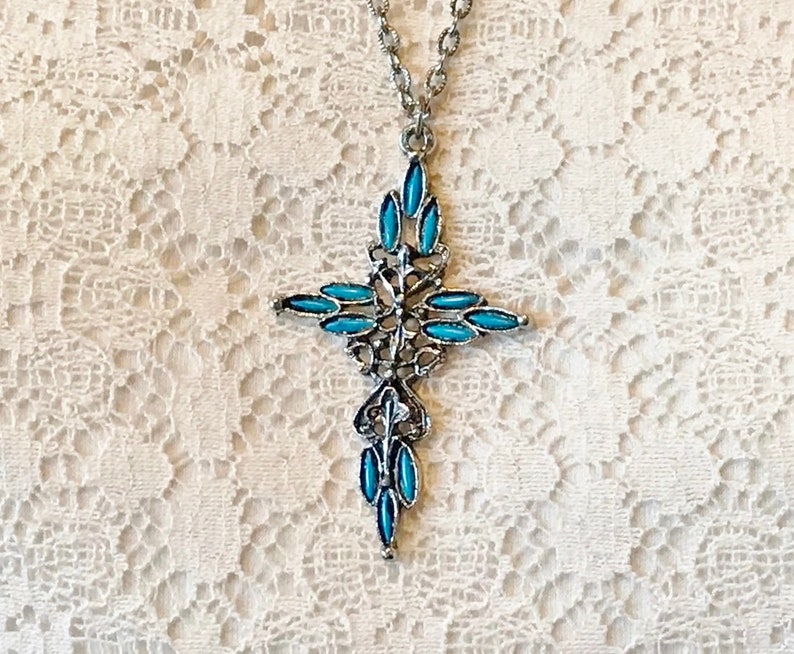 This vintage ZUNI styLe Petit PoiNT CroSS NECKLACE is a great pretender!  Turquoise plastic cabochons mimic the petit point jewelry the Zuni Indians are famous for.  They're set in a silver tone metal.  It's a pretty little western cross that comes on a really nice silver rolo chain.  The links have a  nice stamped line pattern.  You'll receive the pendant and 24" chain.