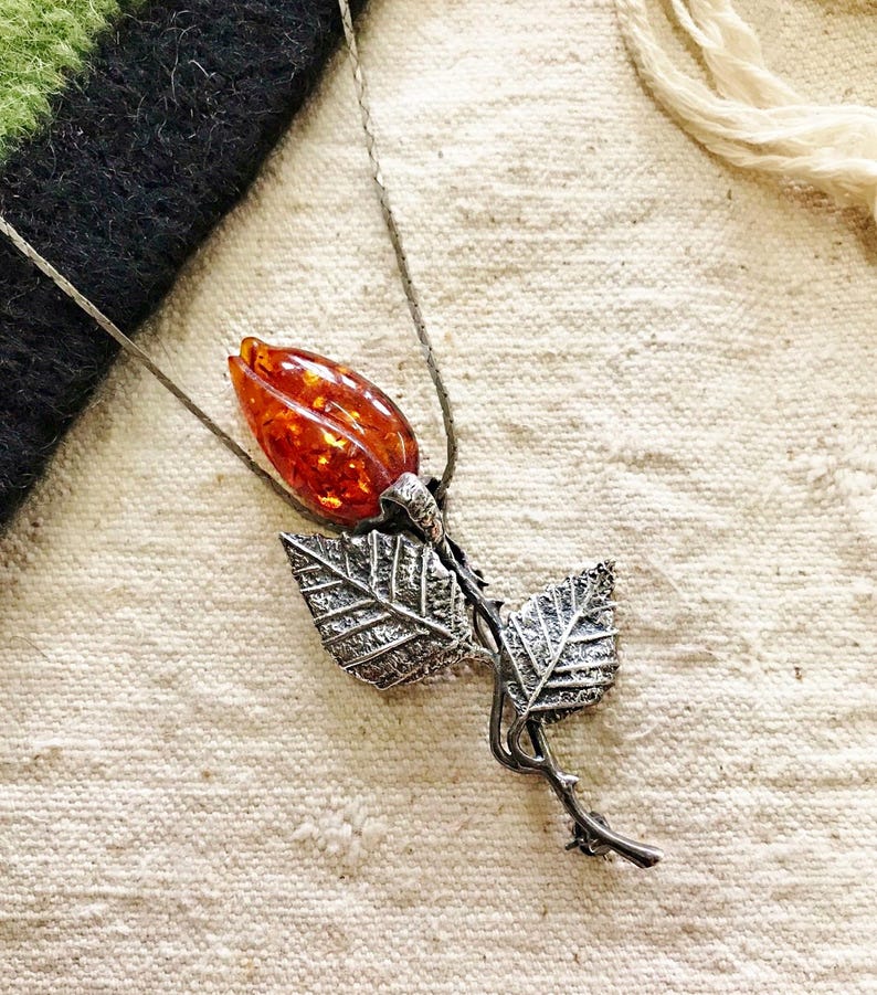 This vintage STERLiNG AMBER ROSE PiN is stunning!  A cognac colored piece of amber has been carved into a rosebud and set in a sterling silver. It's accented with a THORNY stem and two VERY realistic leaves.  PLEASE  check out the leaves.  They're amazing!   It's of course a pin but I kinda like it as a pendant.