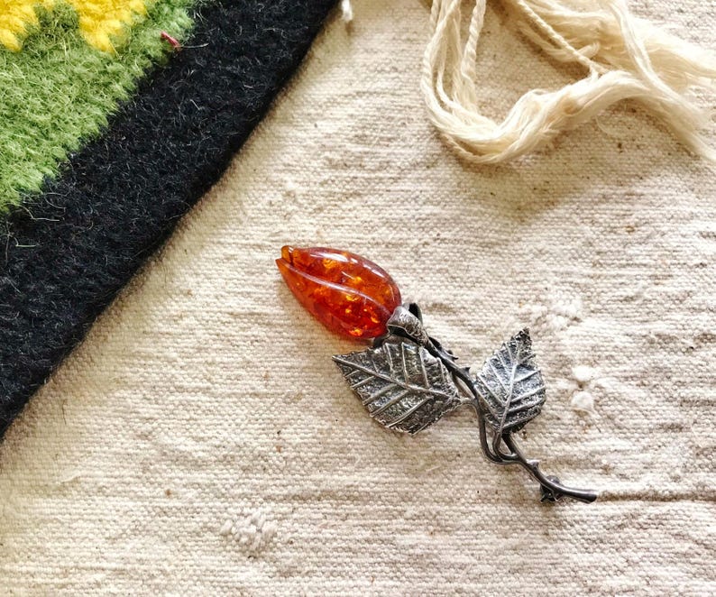 This vintage STERLiNG AMBER ROSE PiN is stunning!  A cognac colored piece of amber has been carved into a rosebud and set in a sterling silver. It's accented with a THORNY stem and two VERY realistic leaves.  PLEASE  check out the leaves.  They're amazing!   It's of course a pin but I kinda like it as a pendant.