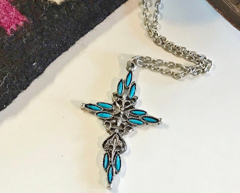 This vintage ZUNI styLe Petit PoiNT CroSS NECKLACE is a great pretender!  Turquoise plastic cabochons mimic the petit point jewelry the Zuni Indians are famous for.  They're set in a silver tone metal.  It's a pretty little western cross that comes on a really nice silver rolo chain.  The links have a  nice stamped line pattern.  You'll receive the pendant and 24" chain.