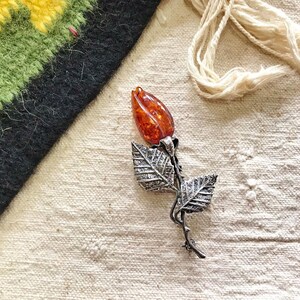 This vintage STERLiNG AMBER ROSE PiN is stunning!  A cognac colored piece of amber has been carved into a rosebud and set in a sterling silver. It's accented with a THORNY stem and two VERY realistic leaves.  PLEASE  check out the leaves.  They're amazing!   It's of course a pin but I kinda like it as a pendant.