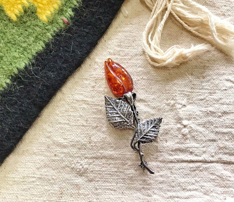 This vintage STERLiNG AMBER ROSE PiN is stunning!  A cognac colored piece of amber has been carved into a rosebud and set in a sterling silver. It's accented with a THORNY stem and two VERY realistic leaves.  PLEASE  check out the leaves.  They're amazing!   It's of course a pin but I kinda like it as a pendant.