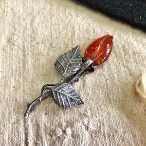 This vintage STERLiNG AMBER ROSE PiN is stunning!  A cognac colored piece of amber has been carved into a rosebud and set in a sterling silver. It's accented with a THORNY stem and two VERY realistic leaves.  PLEASE  check out the leaves.  They're amazing!   It's of course a pin but I kinda like it as a pendant.