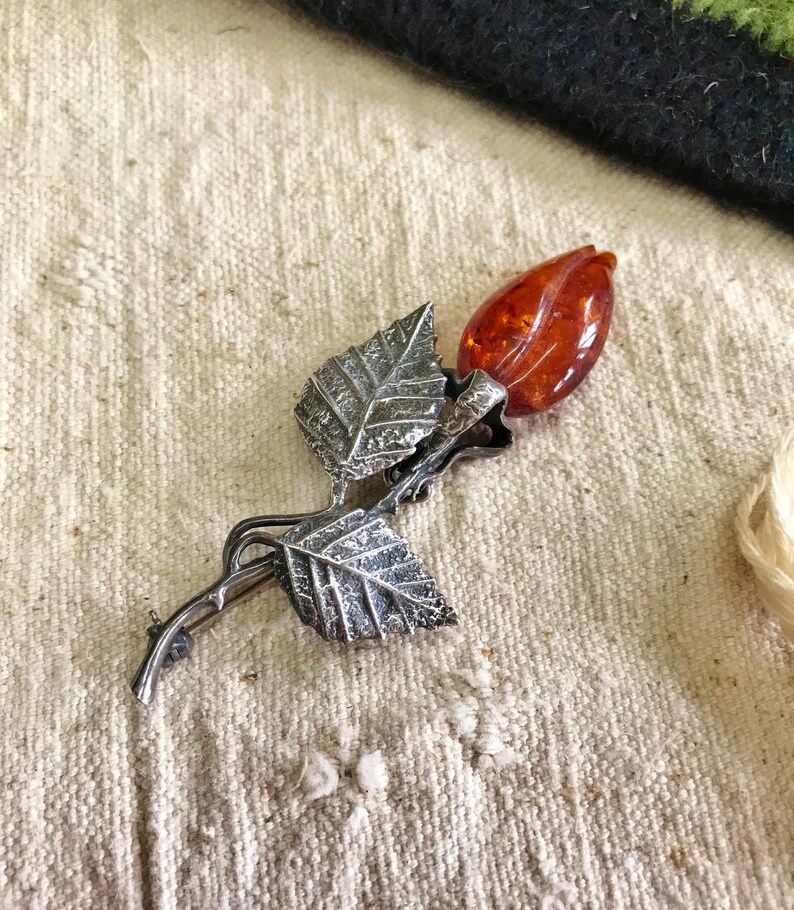 This vintage STERLiNG AMBER ROSE PiN is stunning!  A cognac colored piece of amber has been carved into a rosebud and set in a sterling silver. It's accented with a THORNY stem and two VERY realistic leaves.  PLEASE  check out the leaves.  They're amazing!   It's of course a pin but I kinda like it as a pendant.