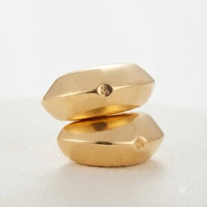 May include: Two gold-toned rings with a smooth, faceted, pebble-like shape stacked vertically. Each ring features a small circular hallmark stamped on the side with the text FC 925, indicating sterling silver construction with a gold finish.