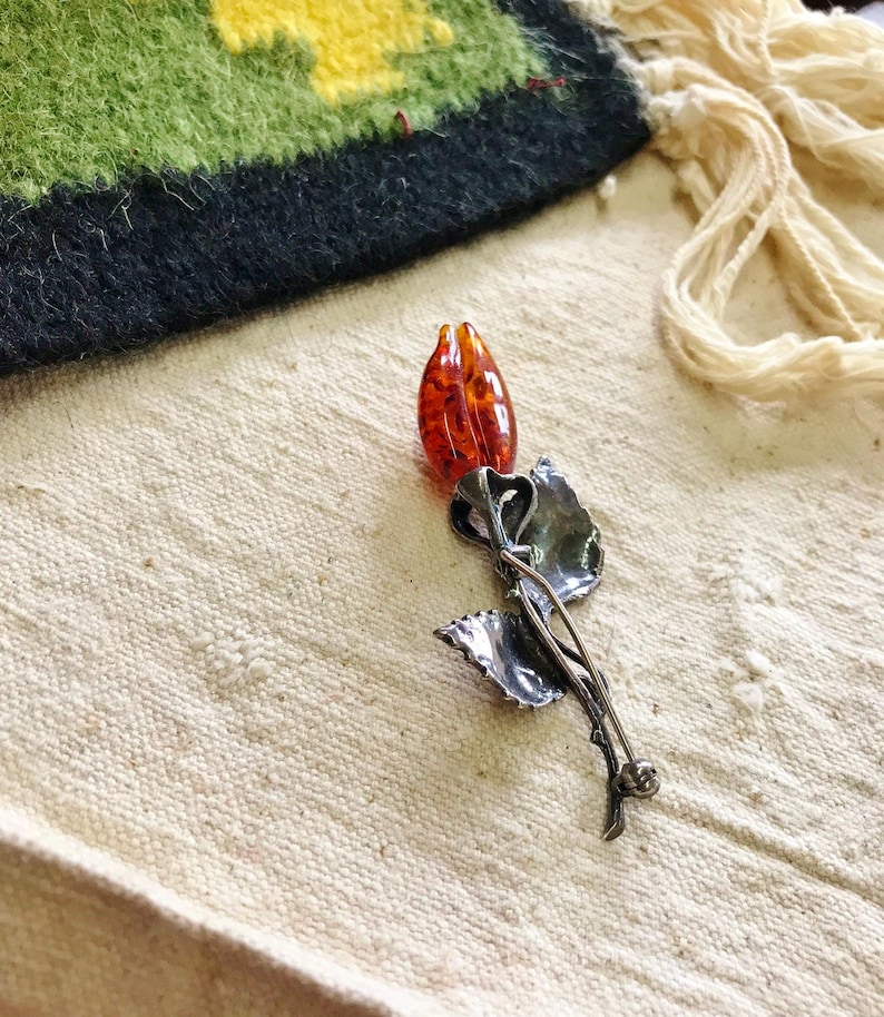 This vintage STERLiNG AMBER ROSE PiN is stunning!  A cognac colored piece of amber has been carved into a rosebud and set in a sterling silver. It's accented with a THORNY stem and two VERY realistic leaves.  PLEASE  check out the leaves.  They're amazing!   It's of course a pin but I kinda like it as a pendant.