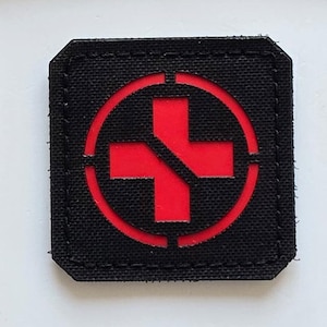 May include: Three black patches. The top patch has three coloured lion figures and the text "LASER PATCH" in white. The bottom patch has a red cross within a red circle.