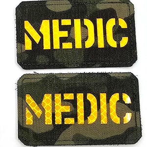 May include: Three rectangular patches. The top patch is black with a white and black shield-shaped logo that says "LASER PATCH" and three lion figures. The middle and bottom patches are camouflage with the word "MEDIC" in yellow.