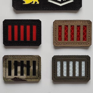 Könnte beinhalten: Eine Sammlung taktischer Aufnäher. Der obere Aufnäher ist schwarz mit einem weißen Diamanten mit dem Text "LASER PATCH" und drei farbigen Löwenfiguren. Darunter befinden sich vier rechteckige Aufnäher mit verschiedenen Farbschemata, darunter Rot, Braun und Tarnmuster.