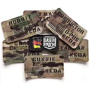 Könnte beinhalten: Eine Sammlung von neun Tarnflecken mit schwarzem Text und amerikanischem Flaggenmuster. Die Patches beinhalten die Wörter "Hobbit", "Y May", "Conductor", "O-Pos NKDA", "GOAT", "CRZ", "LASER PATCH", "NKDA" und "GUNNIE".
