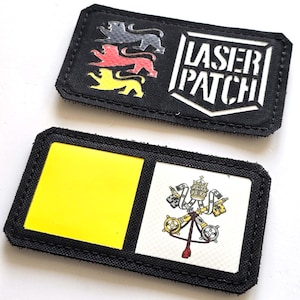 Könnte beinhalten: Zwei schwarze rechteckige Aufnäher. Einer zeigt drei Löwensilhouetten in Grau, Rot und Gelb und den Text "LASER PATCH" in Weiß. Der andere Aufnäher hat ein gelbes Quadrat und ein Wappen.
