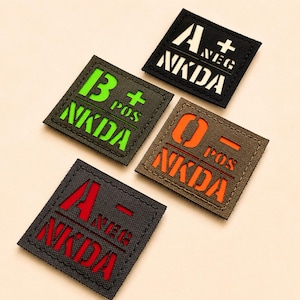May include: Four square patches with blood type information. The patches are black, green, and brown with white, red, and orange text. Each patch displays a blood type (A+, A-, B+, O+). The text "NKDA" is also on each patch.